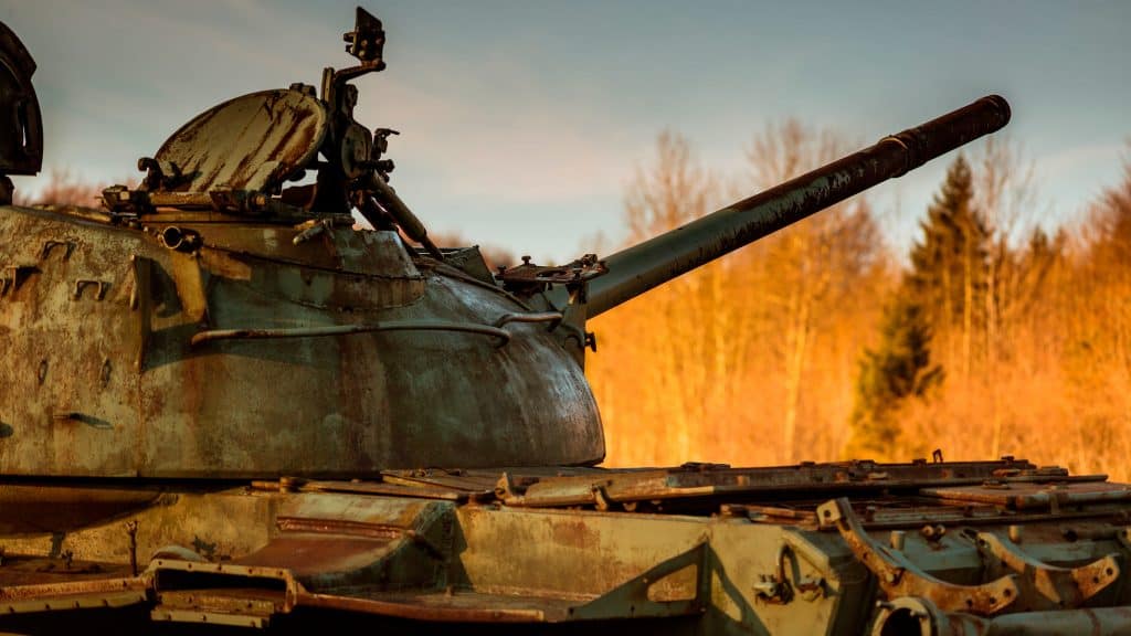 Tanque de guerra apontando canhão para o alto em floresta