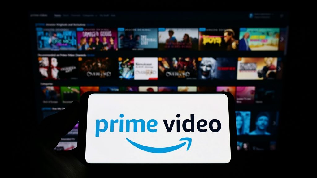 TV, ao fundo, com catálogo do Prime Video; à frente, logo do Prime Video em um smartphone deitado