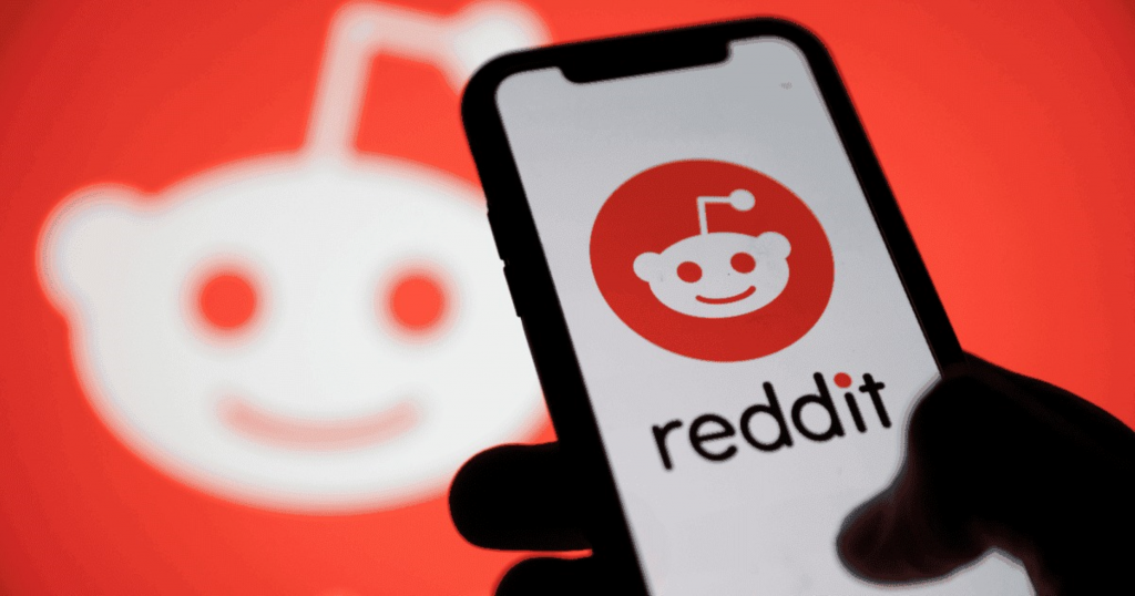 Logo do reddit ao fundo e em um smartphone, mais à frente