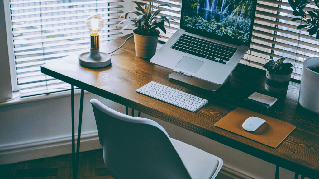 imagem mostra um home office com notebook, mouse e teclado