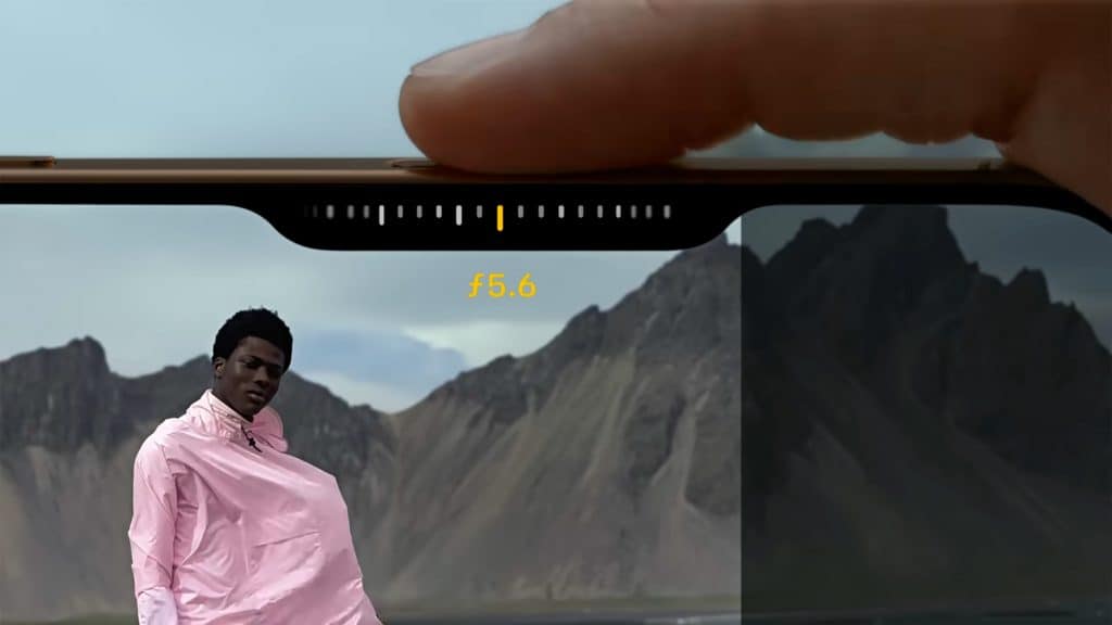 Pessoa com dedo sobre botão Controle da Câmera no iPhone 16 Pro ajustando abertura da lente em foto de pessoa no estilo retrato